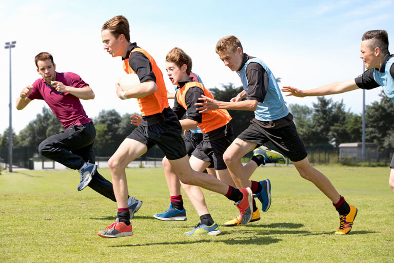 PE Teacher, teaching male students in a secondary school setting.