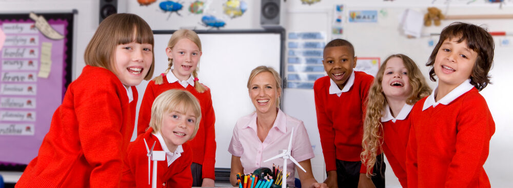 Image of children wearing red uniform in a classroom setting with a female teacher